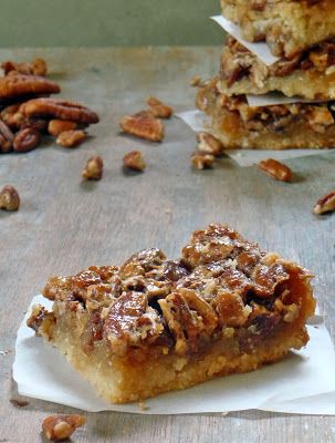 two pieces of pecan pie sitting on top of a wooden table next to other pecans