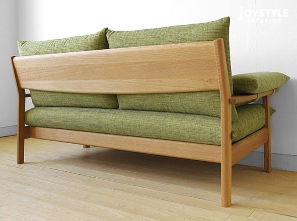 a green couch sitting on top of a hard wood floor next to a white wall