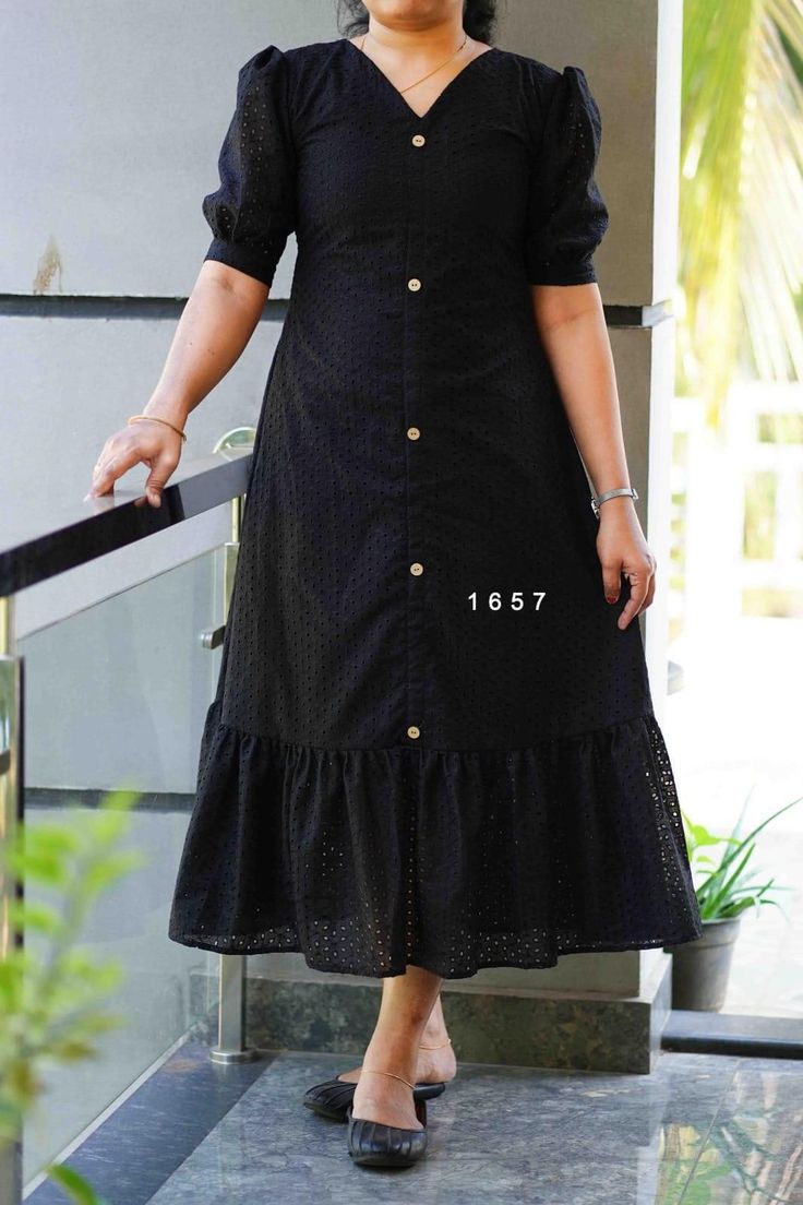 a woman in a black dress is standing on the stairs and smiling at the camera