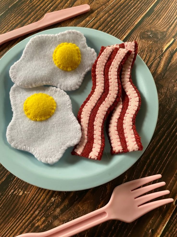 two eggs and bacon on a plate with pink forks