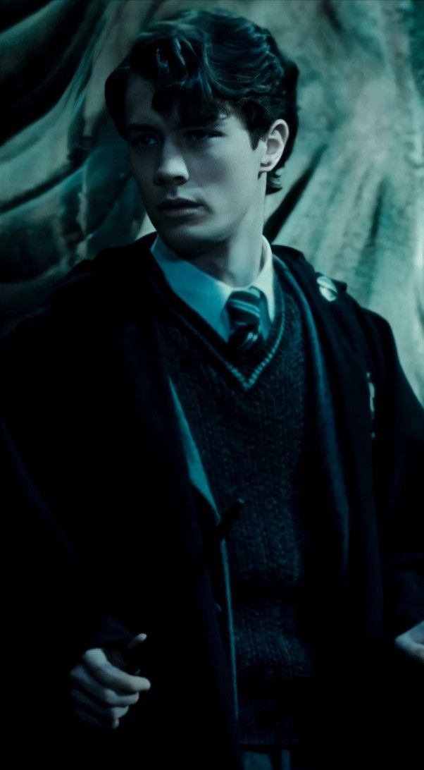 the young man is dressed in harry potter robes and holding his hand on his hip