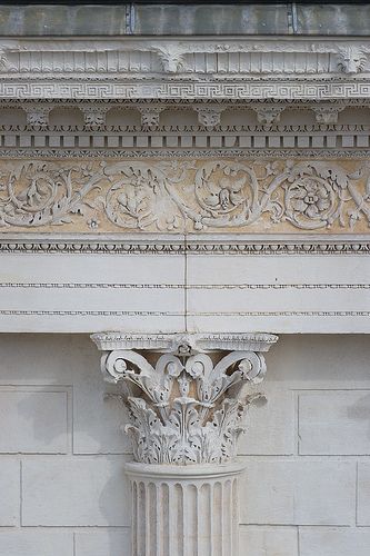 the corner of an old building with a clock on it's face and columns