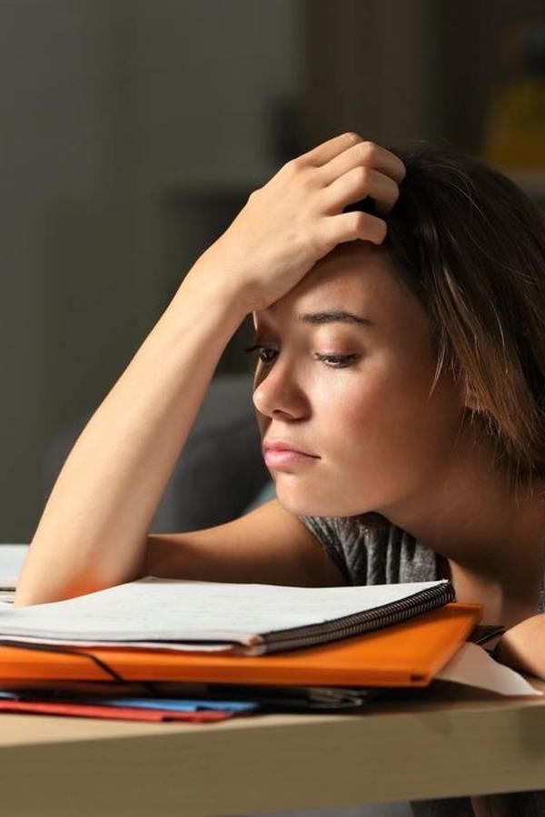 a woman is sitting at a desk with her head in her hands and reading a book