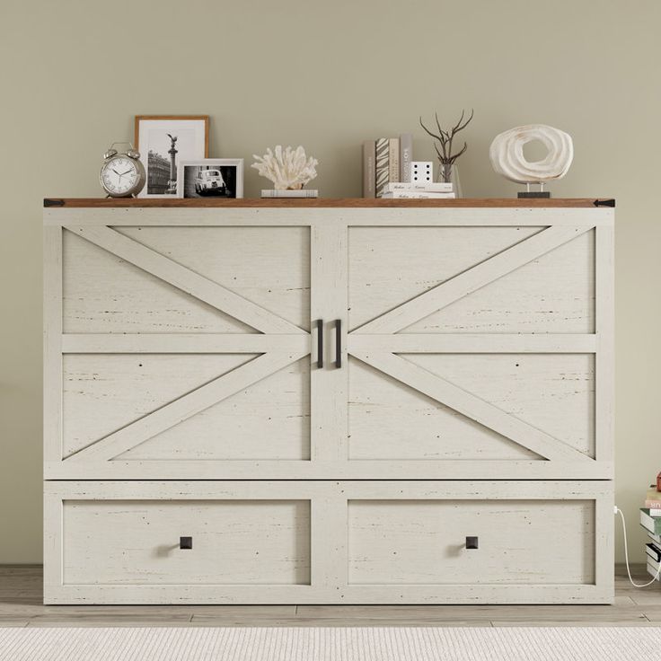 a white cabinet with two doors and some pictures on the top shelf next to it