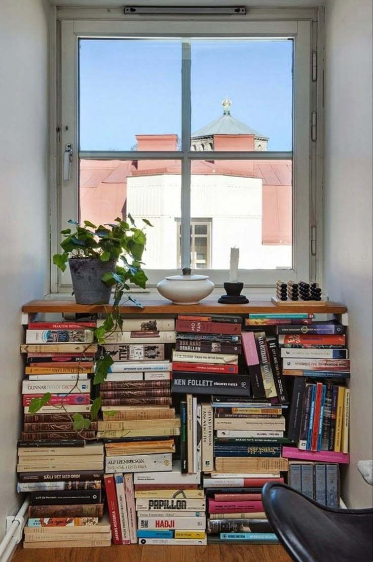 a bookshelf full of books in front of a window with a potted plant