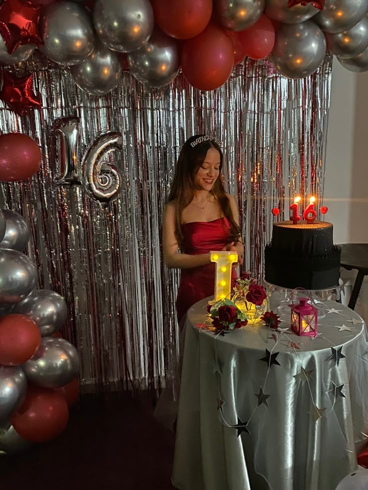 a woman standing in front of a table with a cake on it and balloons behind her