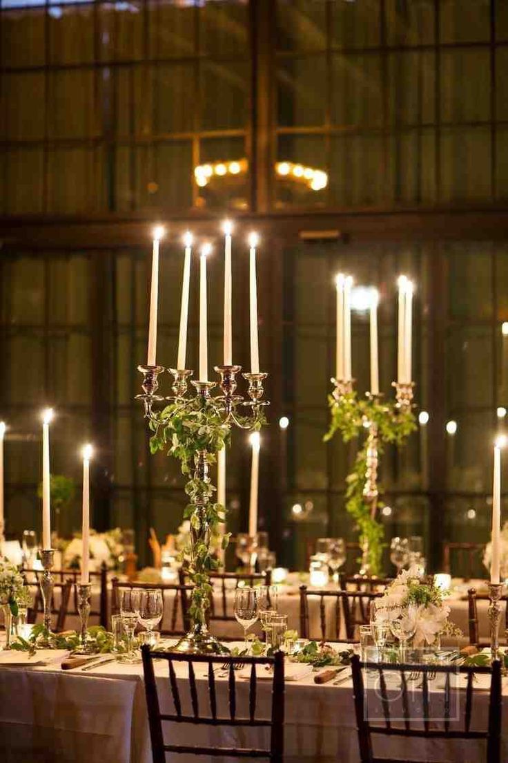 the wedding table is set with candles and greenery