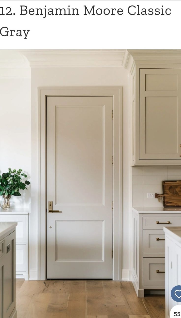 an open door in a white kitchen with wood floors and cabinets on either side of the door