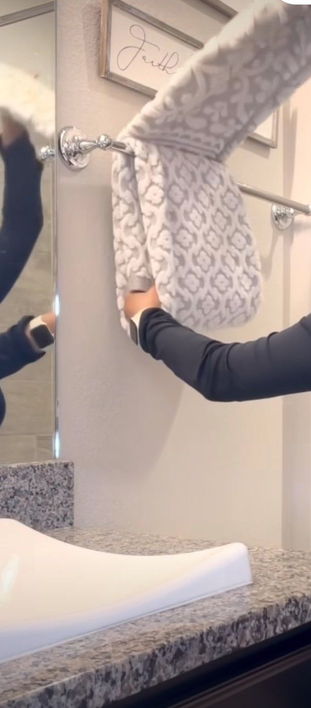 a woman is doing something in front of the mirror with her hands and arm extended