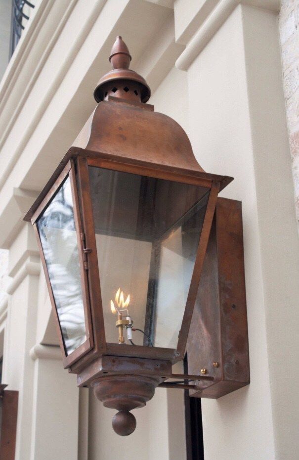 an old - fashioned light fixture on the side of a building with two lit candles