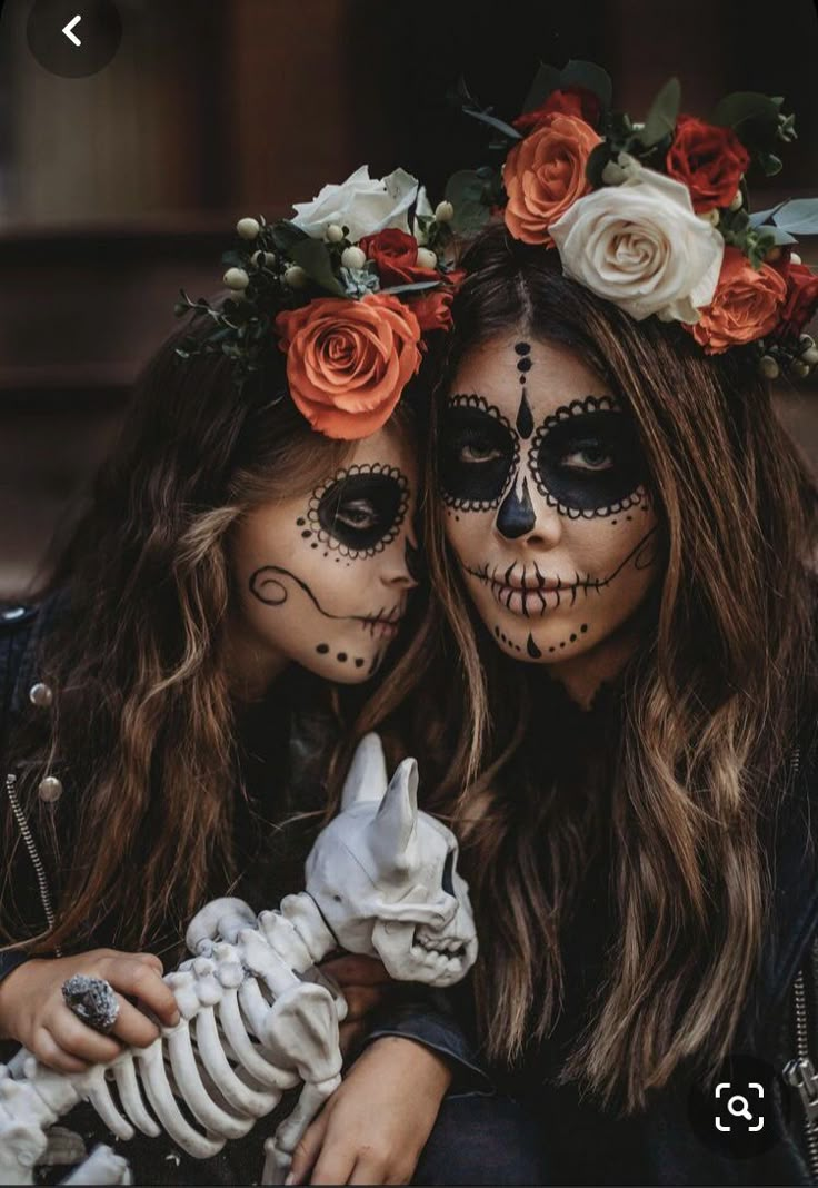 two women with face paint and flowers on their heads, one is holding a doll