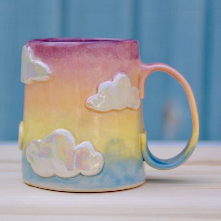 a coffee mug with clouds painted on it