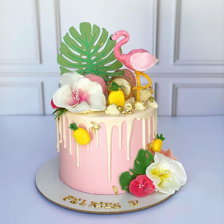 a pink cake decorated with flowers and flamingos