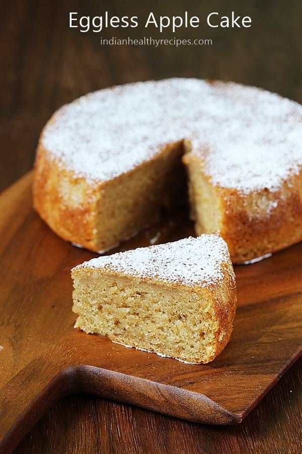 an eggless apple cake on a wooden cutting board with one slice cut from it