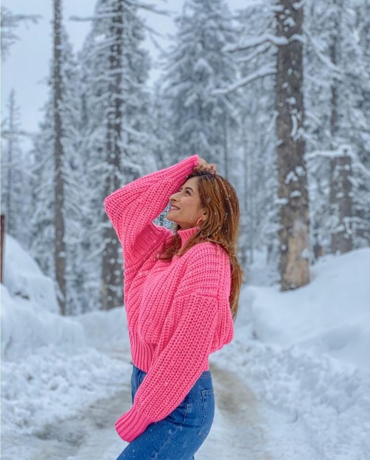 a woman standing in the snow with her hands on her head