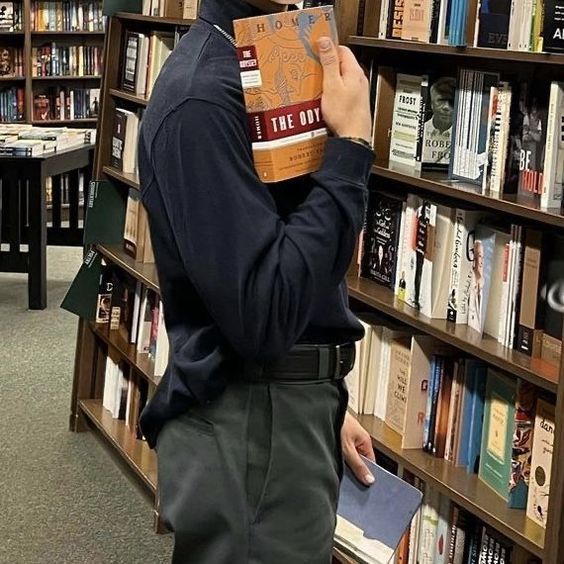 a man standing in front of a bookshelf holding a book