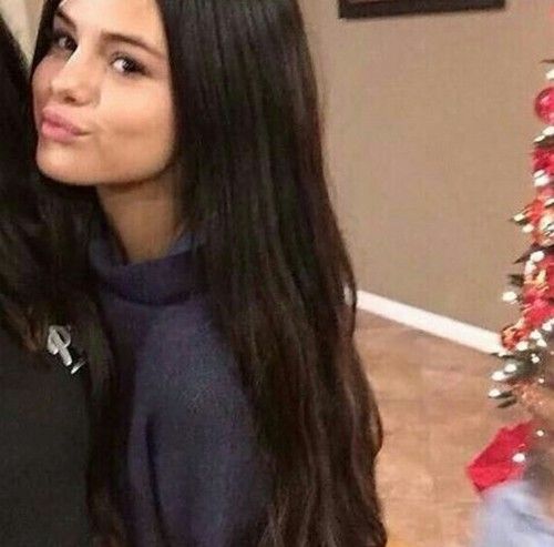 two women standing next to each other in front of a christmas tree and looking at the camera