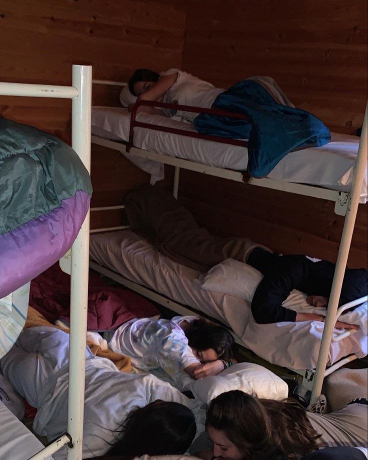 several people sleeping on bunk beds in a room with wood walls and flooring,