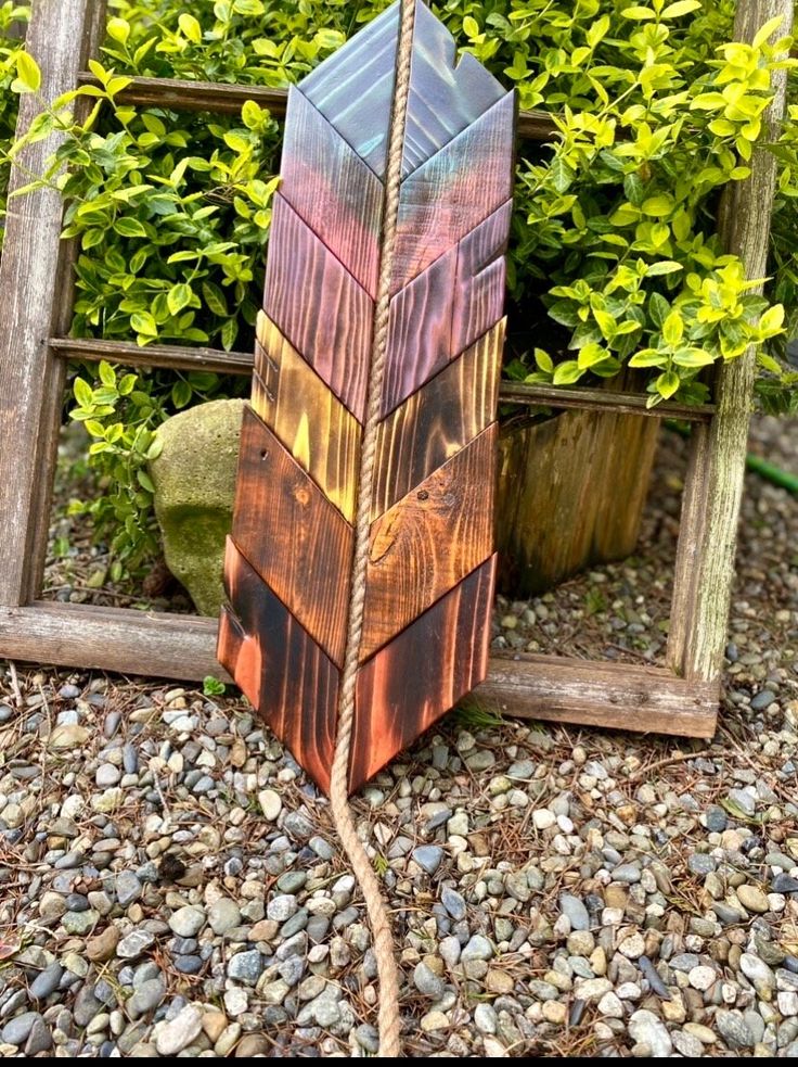 a wooden sculpture sitting on top of a gravel covered ground next to a planter