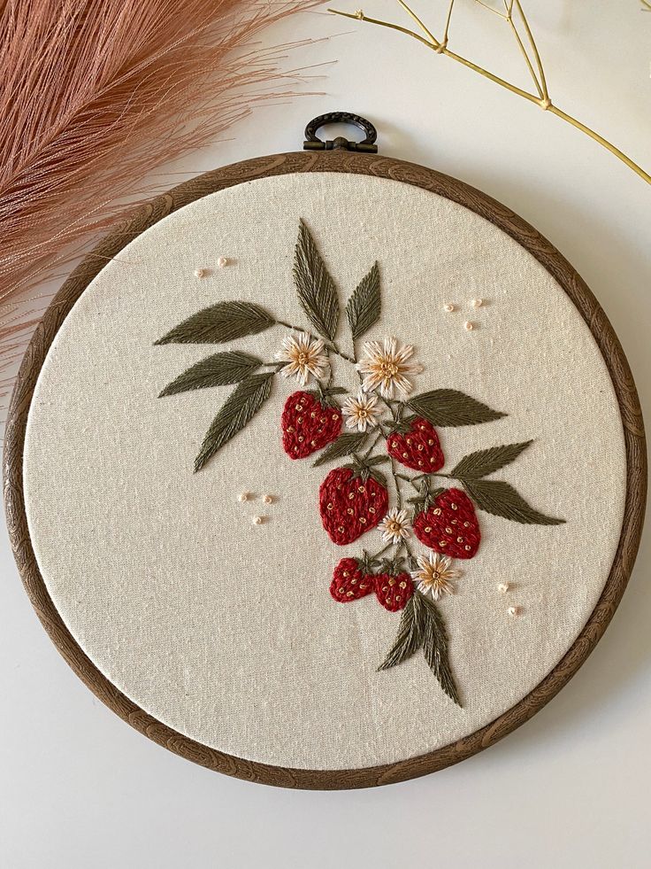 a close up of a embroidery on a white surface with flowers and berries in it