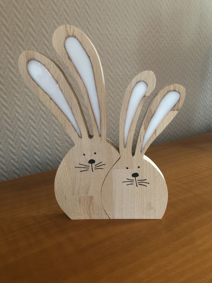 two wooden rabbits with faces cut out of them