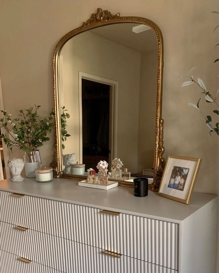 a dresser with a mirror, vases and pictures on it