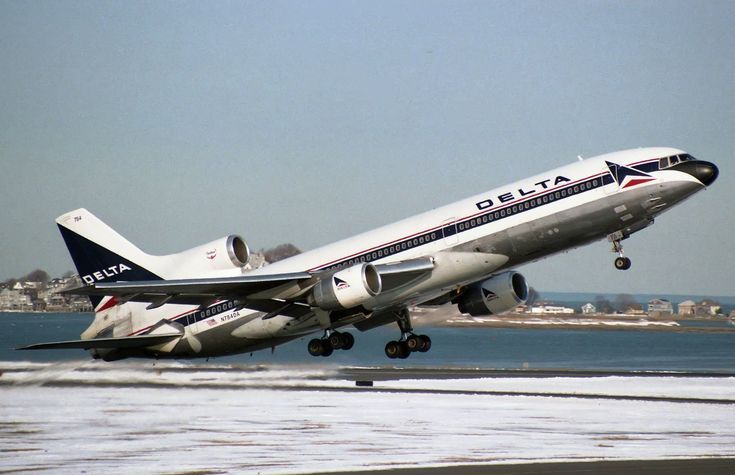 a large jetliner taking off from an airport runway with water in the foreground