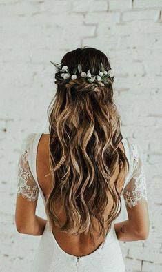 the back of a woman's head with long hair and flowers in her hair