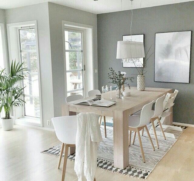 a dining room table with white chairs and pictures on the wall