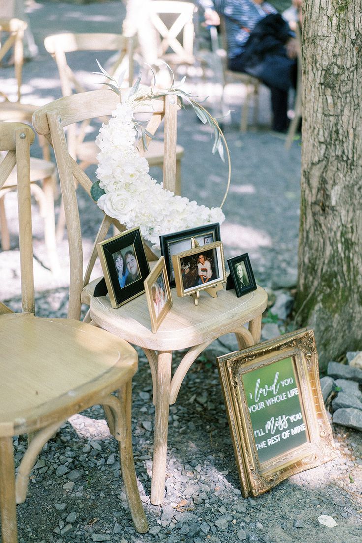 a wooden chair sitting next to a table with pictures and frames on top of it