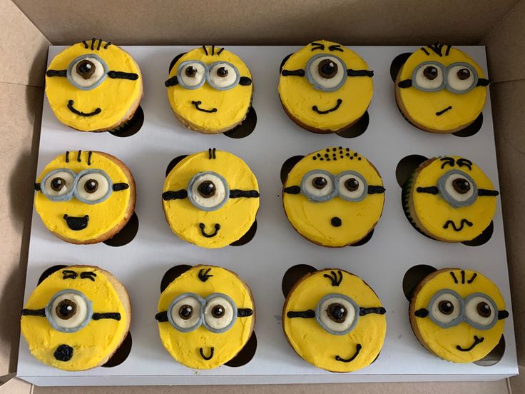 twelve cupcakes with yellow frosting decorated like minion's and eyes