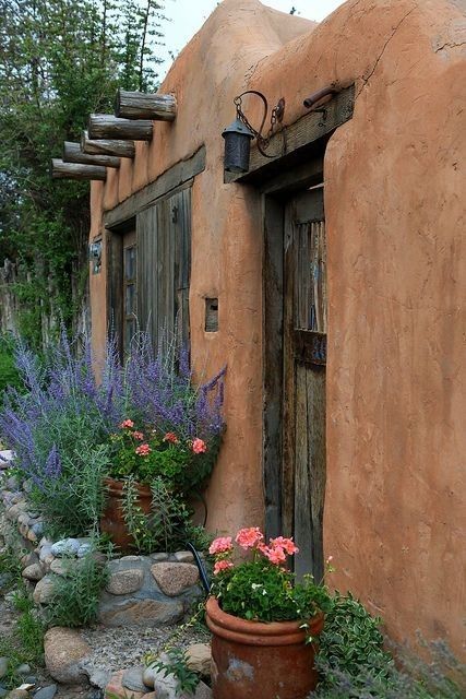 an adobe building with flowers and plants in front