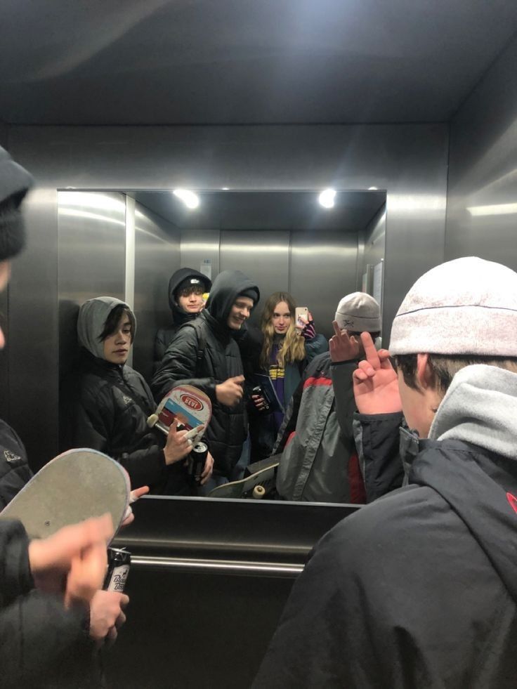 a group of people standing in front of a mirror with one person holding a skateboard