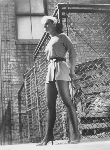 a woman standing in front of a fence holding a tennis racquet