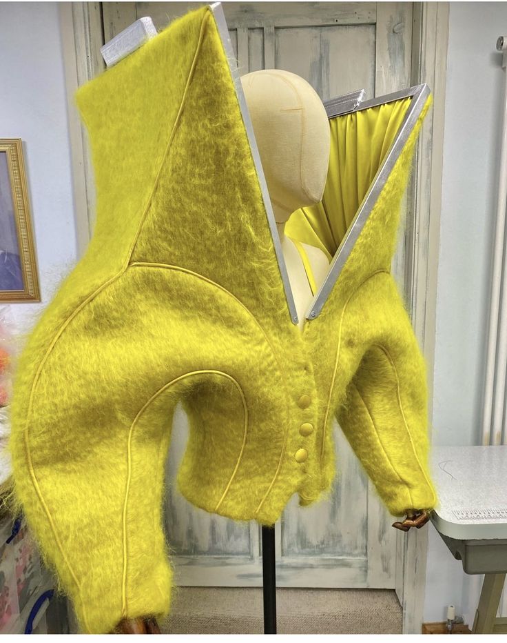 a mannequin's head is covered in bright yellow fabric and sits next to a white table