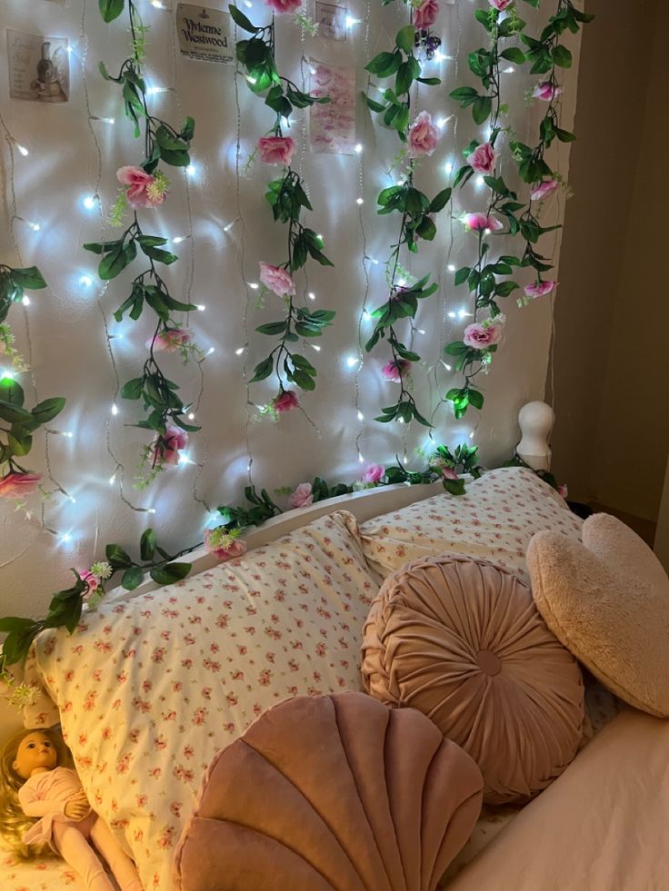 there is a bed with pillows and lights on the wall behind it that are decorated with pink flowers