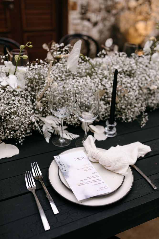 the table is set with white flowers and silverware