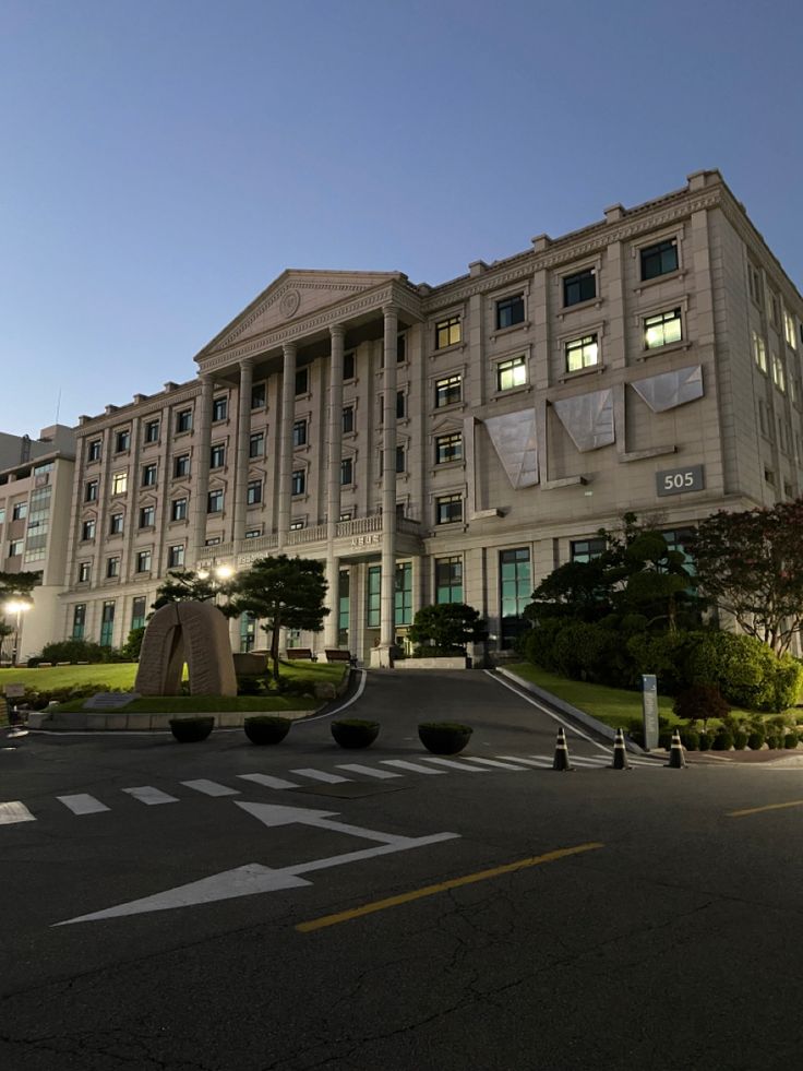 a large building with many windows and lights on it's sides in the evening