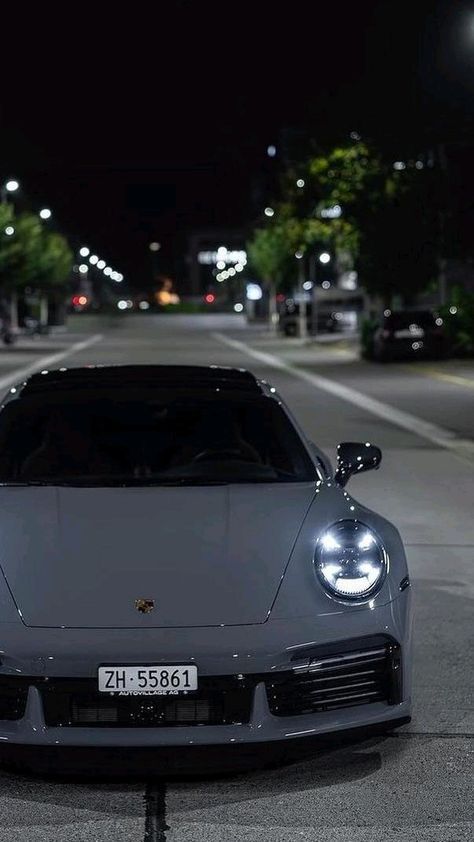 a silver sports car parked on the side of a road at night with its lights on