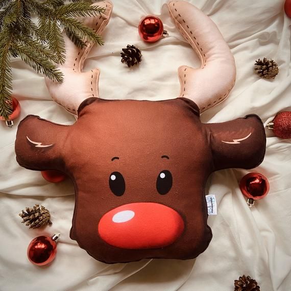 a reindeer pillow on a bed with christmas decorations