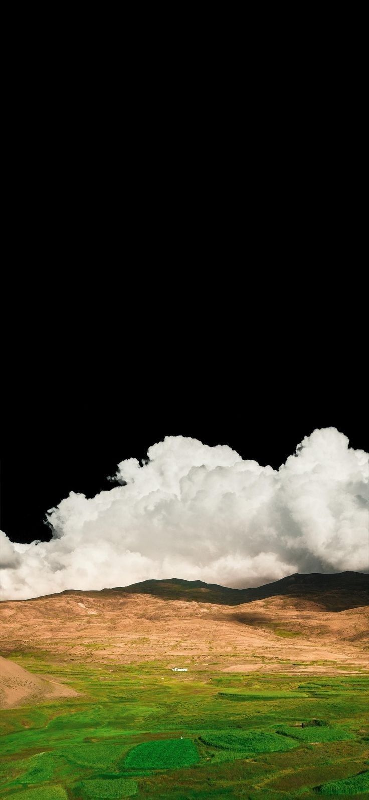 an airplane is flying in the sky with some clouds above it and green grass below