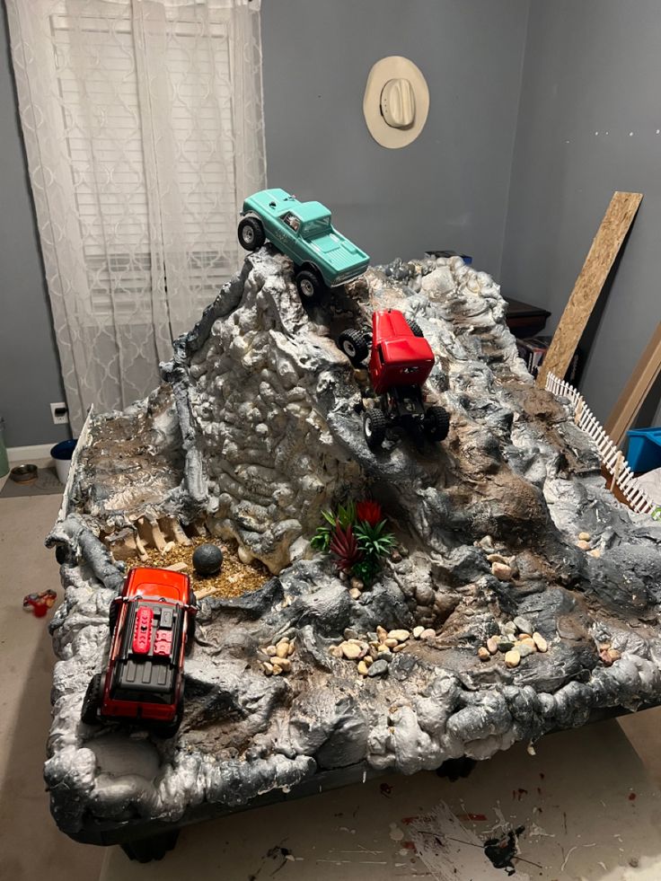 two toy trucks are parked on top of a rock in the middle of a room