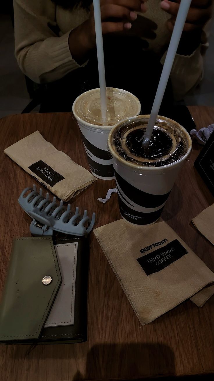 a table topped with a cup of coffee next to a wallet and cell phone charger