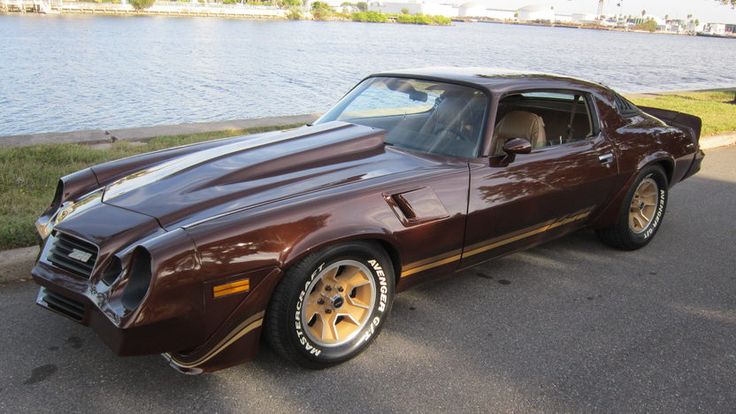 a brown car parked on the side of a road next to a body of water