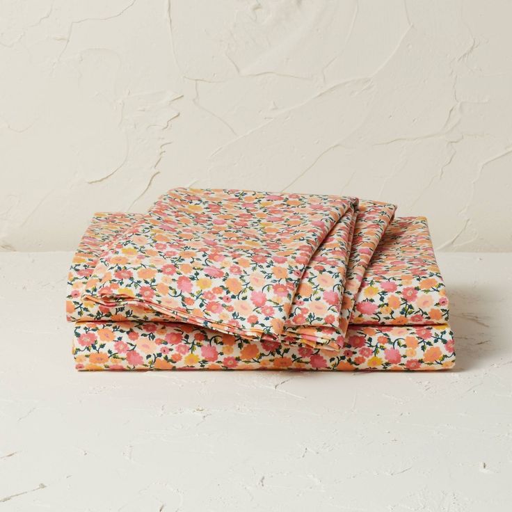 the pink and orange floral print sheets are folded on top of each other