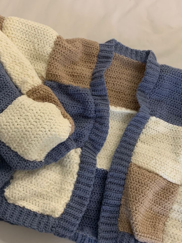 a crocheted sweater with two different colors on the front and one is blue, beige, and white