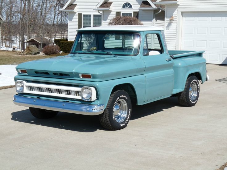 an old blue pickup truck parked in front of a house