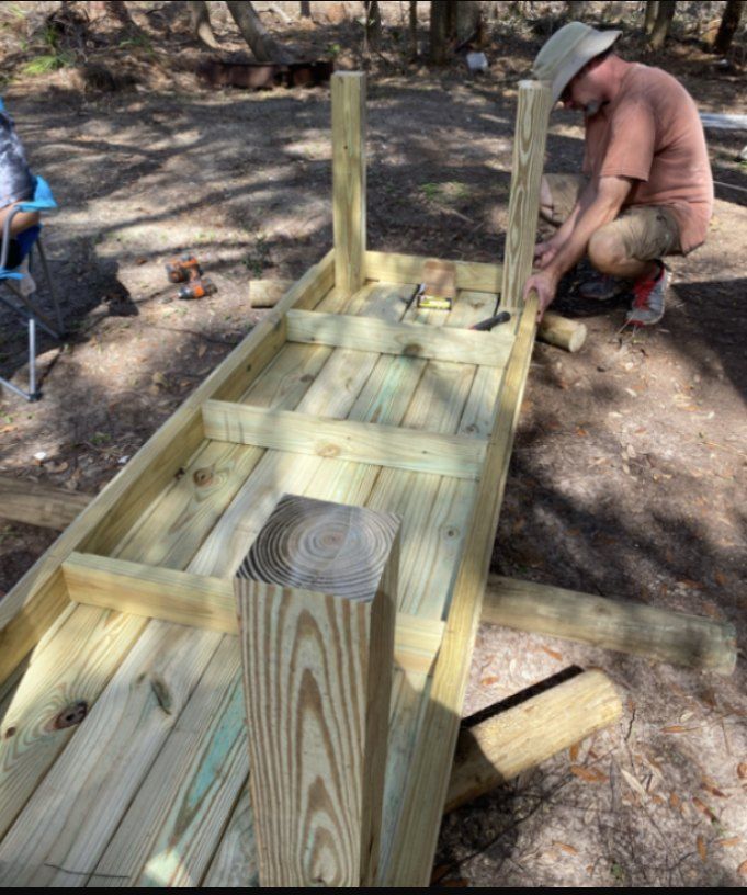 two men working on a wooden structure in the woods