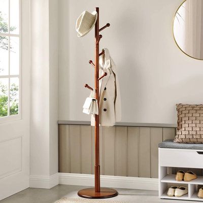 a coat rack with hats, shoes and coats on it in the corner of a room