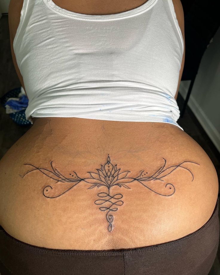 the back of a woman's stomach with a lotus tattoo on it